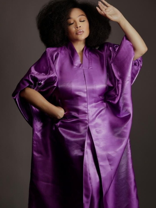 Woman wearing a purple satin dress against a dark background